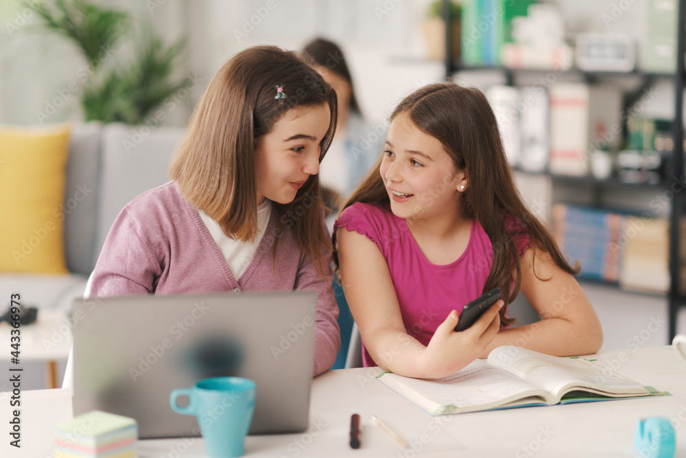 Girls sitting at desk and using a smartphone Girls sitting at desk and using a smartphone