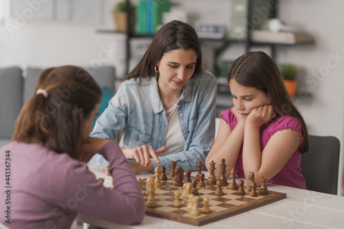 Young mother teaching chess to her kids
