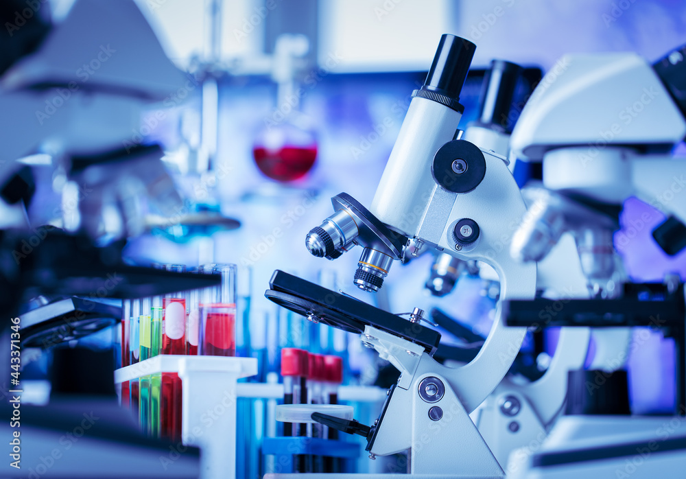 Microscope in and laboratory and test tube equipment in lab blue lights, science and experiment concept Microscope in and laboratory and test tube equipment in lab blue lights, science and experiment concept