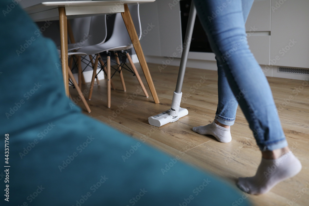Woman cleaning floor in apartment with vacuum cleaner closeup Woman cleaning floor in apartment with vacuum cleaner closeup