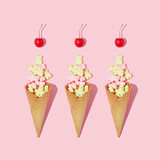 Creative composition or pattern with ice cream cones, yellow and pink gummy bears and bright red cherries on pastel pink background. Summer dessert art direction. Summer food aesthetic concept.