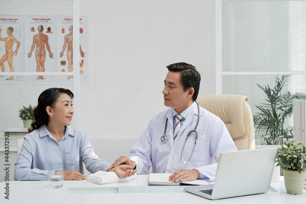 General practitioner talking to senior patient and taking her pulse before examination General practitioner talking to senior patient and taking her pulse before examination