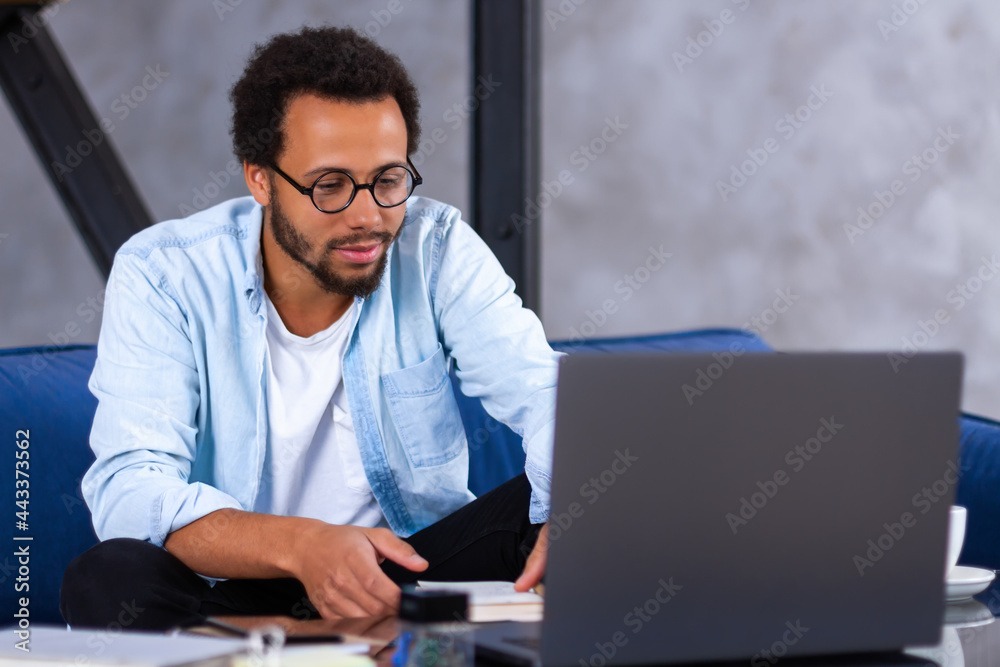 An African-American smiling businessman using laptop computer app for communication with diverse team on distance. Black man freelancer is talking with colleagues online. Video meeting concept. An African-American smiling businessman using laptop computer app for communication with diverse team on distance. Black man freelancer is talking with colleagues online. Video meeting concept.