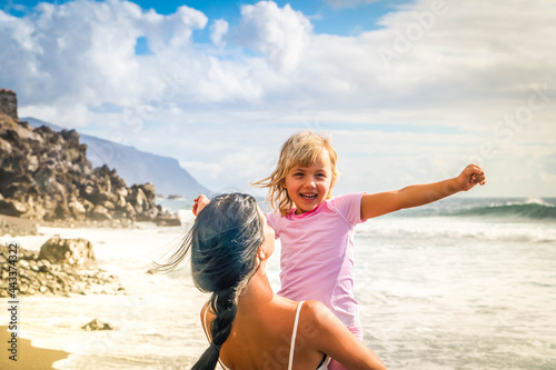 Happy little girl daughter enjoying vacation with mother while standing on beach © neirfy
