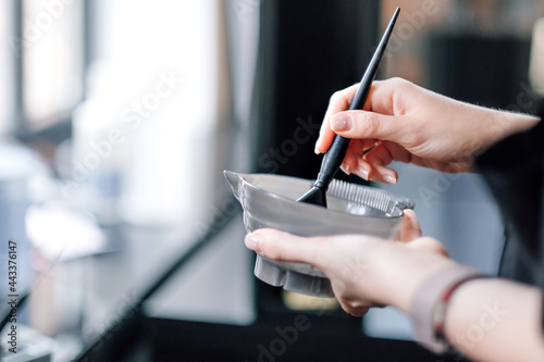 Hairdresser holding bowl with hair dye in beauty salon photo