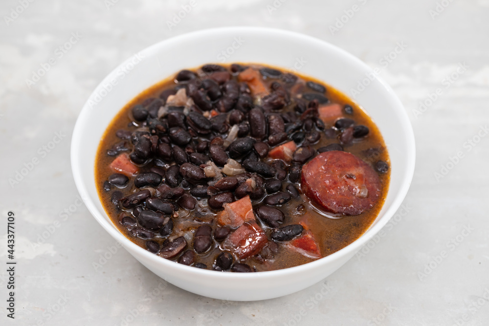 black beans with meat and sausages in white bowl black beans with meat and sausages in white bowl