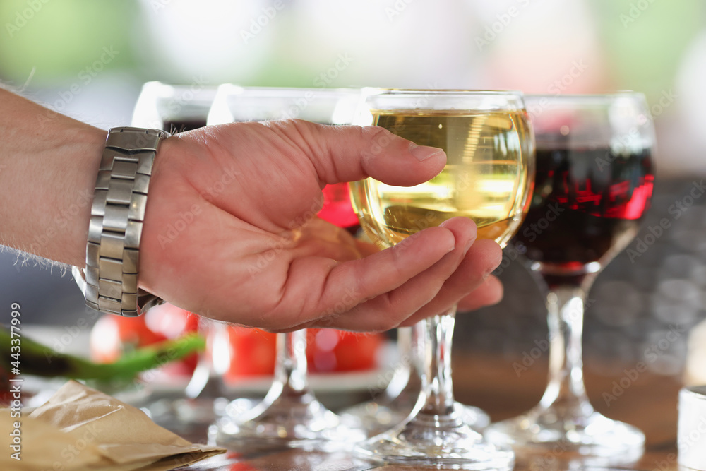 Man hand taking glass of white wine in restaurant closeup