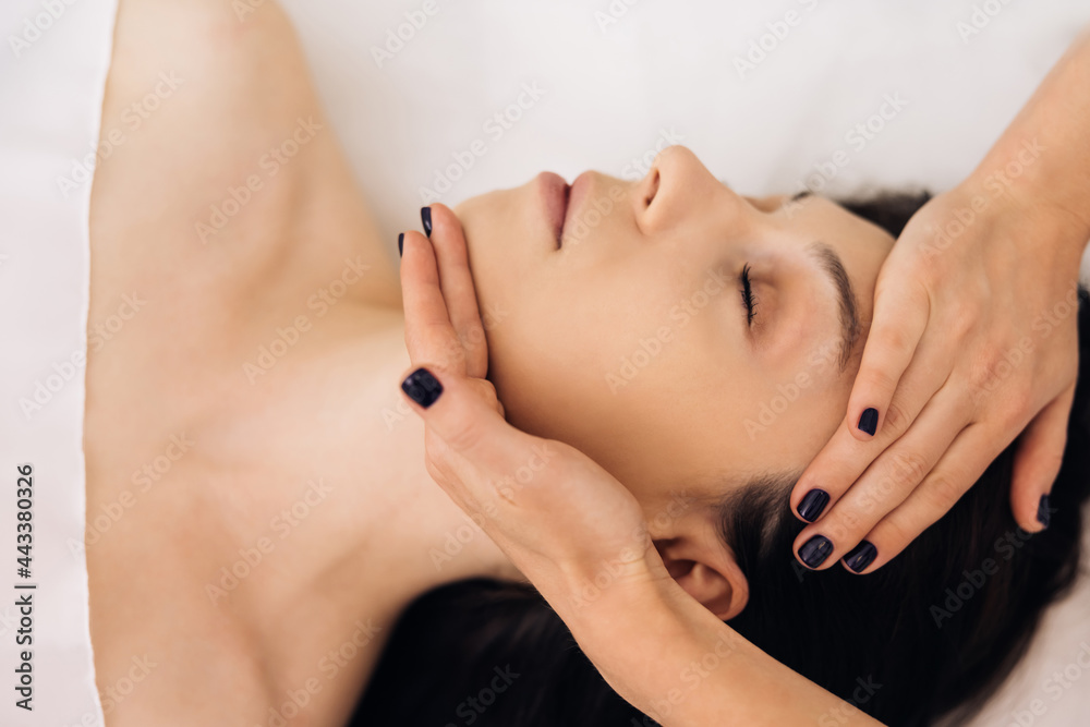 Young Caucasian woman lying on spa bed get facial massage treatment with aroma essential oil skincare from massage therapist at beauty salon. Wellness health care body massage spa concept
