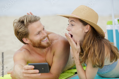 couple on the beach looking shocked at smartphone content © auremar