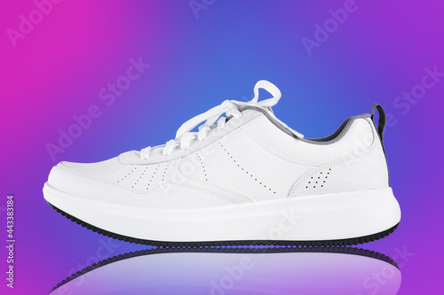 White new sneaker on neon color background with reflection. Sport shoe close up. Street fashion style
