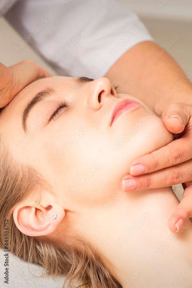 Young caucasian woman receiving a head and chin massage in a spa medical center