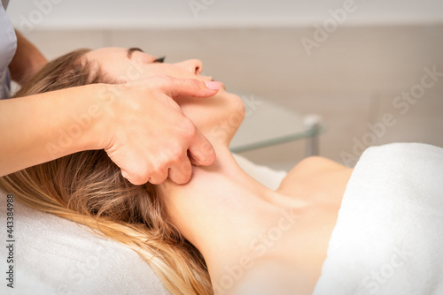 Beautician making lymphatic drainage face massage or facelifting massage at the beauty salon photo