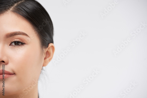Half face of beautiful young woman looking at camera, isolated on white
