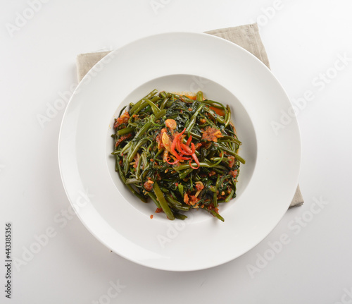 stir fried kang kong vegetable with spicy sambal chilli sauce in plate on white table chinese restaurant asian cafe vegan halal menu photo