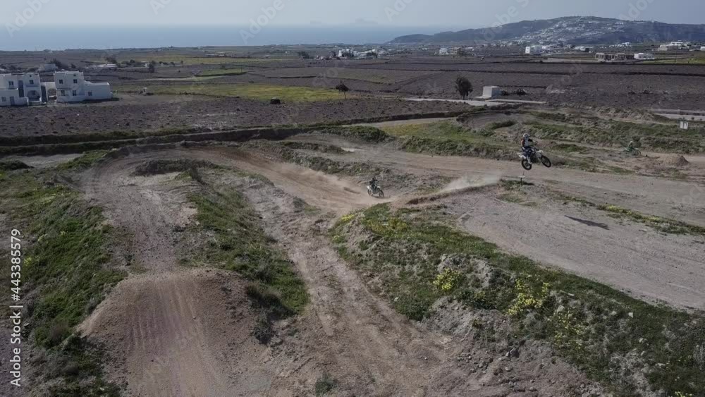 Drone shot of two motocross riders on as they hit a jump on dirt track. Drone shot of two motocross riders on as they hit a jump on dirt track.