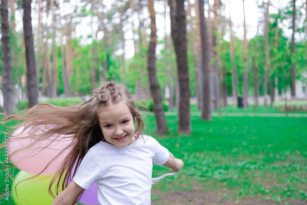 pretty preschool girl having fun playing with hot air balloons outdoors. hollidays, party, birthday, celebration. happy children pretty preschool girl having fun playing with hot air balloons outdoors. hollidays, party, birthday, celebration. happy children