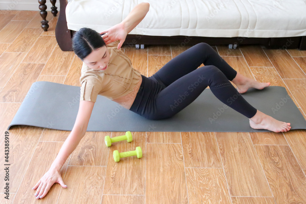 Obraz premium A beautiful young sports girl in leggings and a top goes in for sports at home. Sports online at home, sports lifestyle. Self-isolation is beneficial, fun and online education. Healthy lifestyle