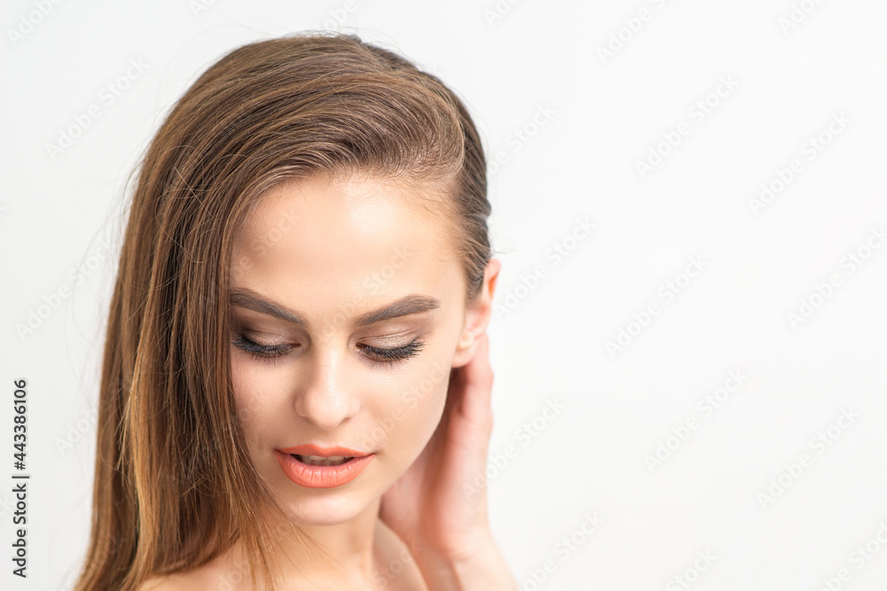 Beautiful young caucasian woman with natural makeup smiling and looking down standing on white background Beautiful young caucasian woman with natural makeup smiling and looking down standing on white background