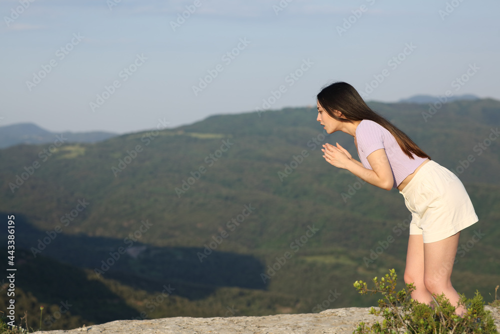 Naklejka premium Scared asian woman looking down on a mountain cliff