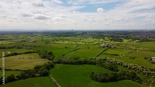 Drone image looking over green farmland with a cloudy sky background. 