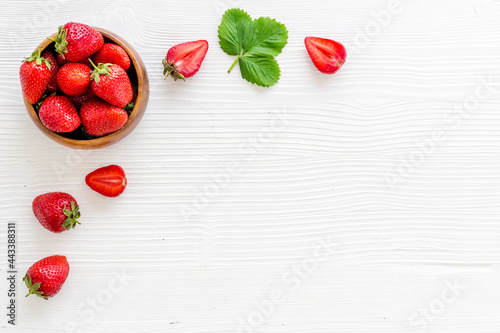 Juicy strawberry with leaves in bowl, top view