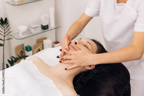 Face Massage in beauty spa salon. Caucasian woman receiving a facial massage at an aesthetic salon. Spa facial Massage. Body care, skin care, wellness, wellbeing, beauty treatment concept © uflypro