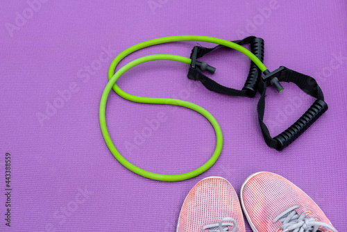 Sneakers, fit tube and a purple fitness mat. Sport concept