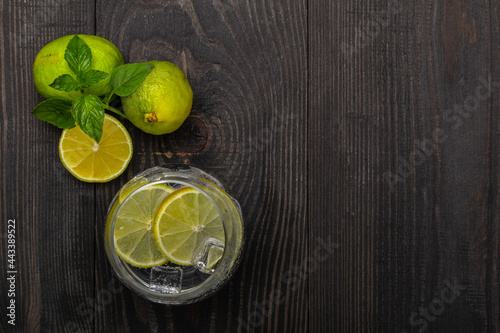 carbonated tonic with ice cubes and lime slices in a glass on a dark wooden background top view