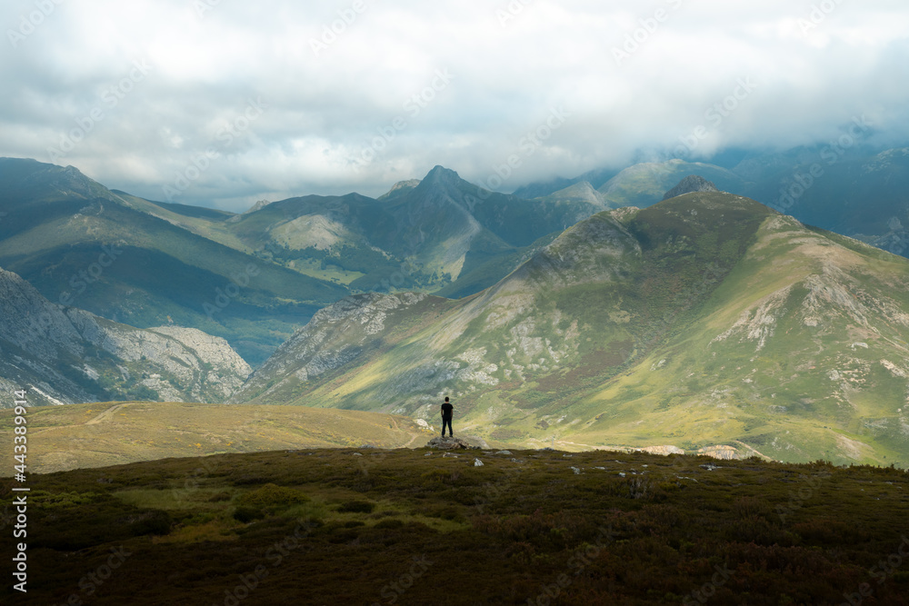 Mountaineer hiking in the San Isidro pass, route of the Absent Lake, located between Asturias and Leon. In the background you can see the Picos de Europa in the Cantabrian Mountains.