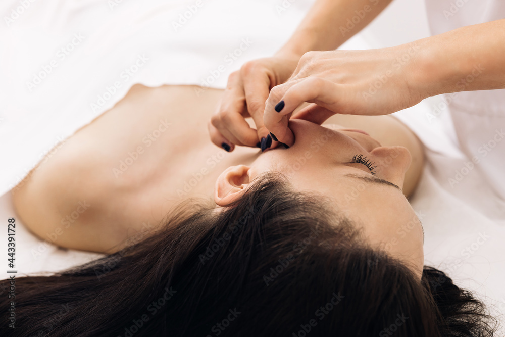 Cosmetologist is touching girl's face. Facial cleansing with professional cosmetic facial massage. Woman is having cosmetic treatment at spa salon Cosmetologist is touching girl's face. Facial cleansing with professional cosmetic facial massage. Woman is having cosmetic treatment at spa salon