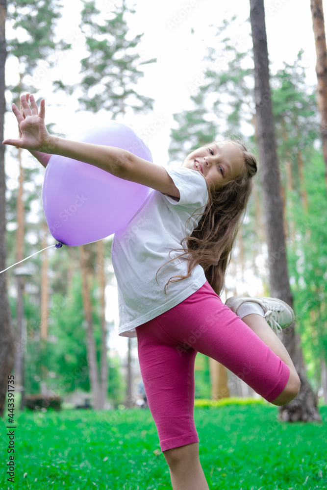 pretty girl in pink leggings and white t-shirt with purple hot air balloon in park. holliday, party, birthday, celebration. happy children