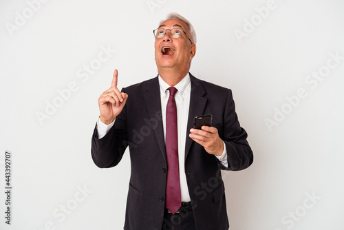 Senior business american man holding mobile phone isolated on white background pointing upside with opened mouth.