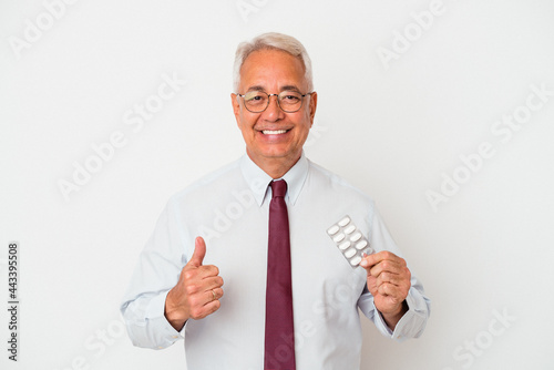 Senior american man holding pills isolated on white background smiling and raising thumb up