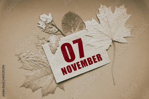 november 07. 07th day of month, calendar date.Envelope with the date and month, surrounded by autumn leaves on brown background.Autumn month, day of year concept photo