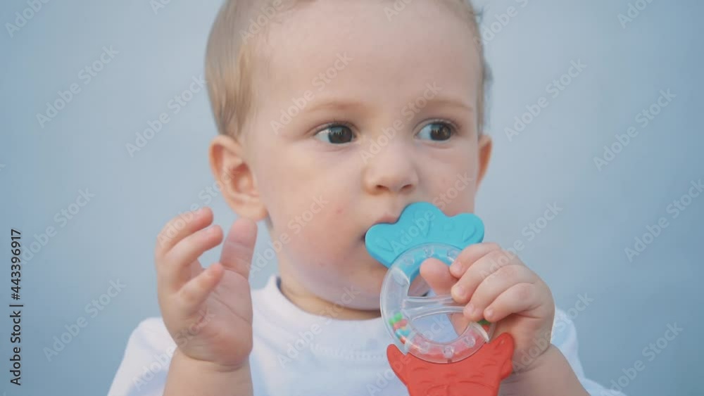 cute baby holds a toy in his hand and puts it in his mouth. Child biting a toy, teething. A cute baby bites and pulls a toy into his mouth. cute baby holds a toy in his hand and puts it in his mouth. Child biting a toy, teething. A cute baby bites and pulls a toy into his mouth.