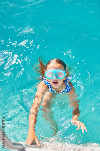 A child in goggles on the steps climbing out of the pool