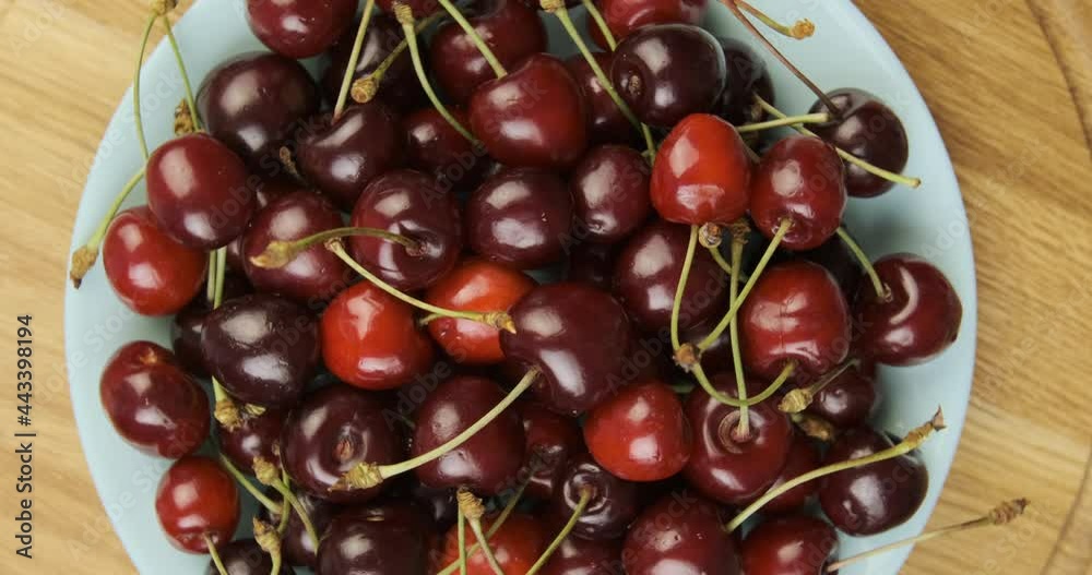 Ripe red cherries on round plate. Summer fresh berries. Rotating turntable clockwise shot. Rotating video. 
