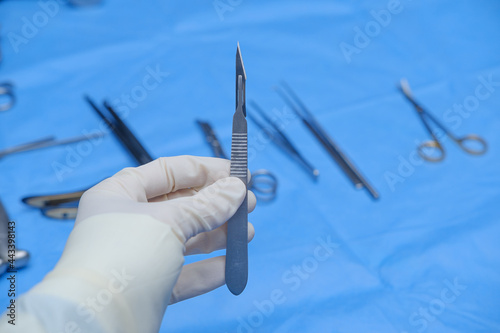 Surgeon holds scalpel in operating theatre