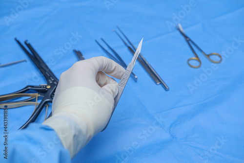 Surgeon holds scalpel in operating theatre