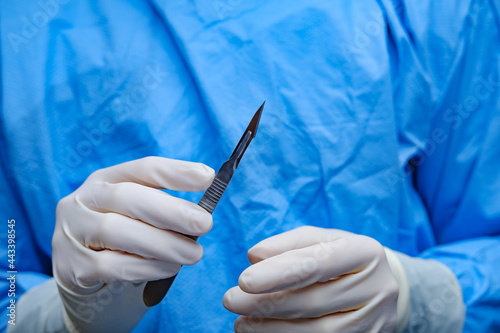 Surgeon holds scalpel in operating theatre