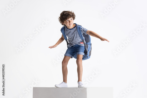 Fototapeta Naklejka Na Ścianę i Meble -  Caucasian preschool boy standing on big box isolated over white studio background. Copyspace. Childhood, education, emotions concept