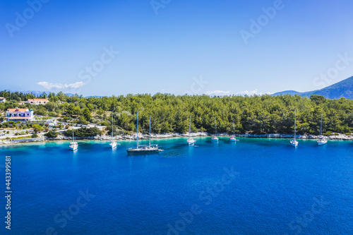 Aerial photo of sailing boats docked in blue bay of Fiskardo, Kefalonia island, Ionian, Greece