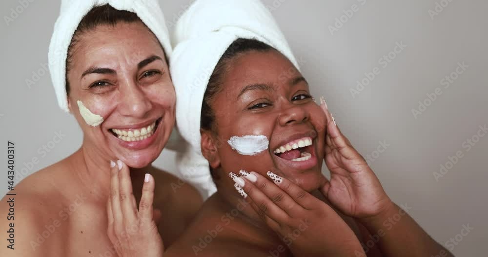 Mature latin and african young women having fun doing beauty day together - Multiracial people doing skin care therapy

