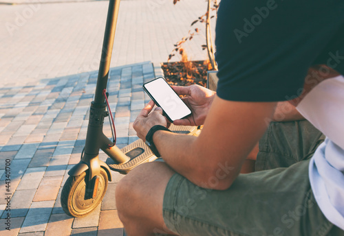 Man standing with electric scooter and showing the phone with blank white screen photo