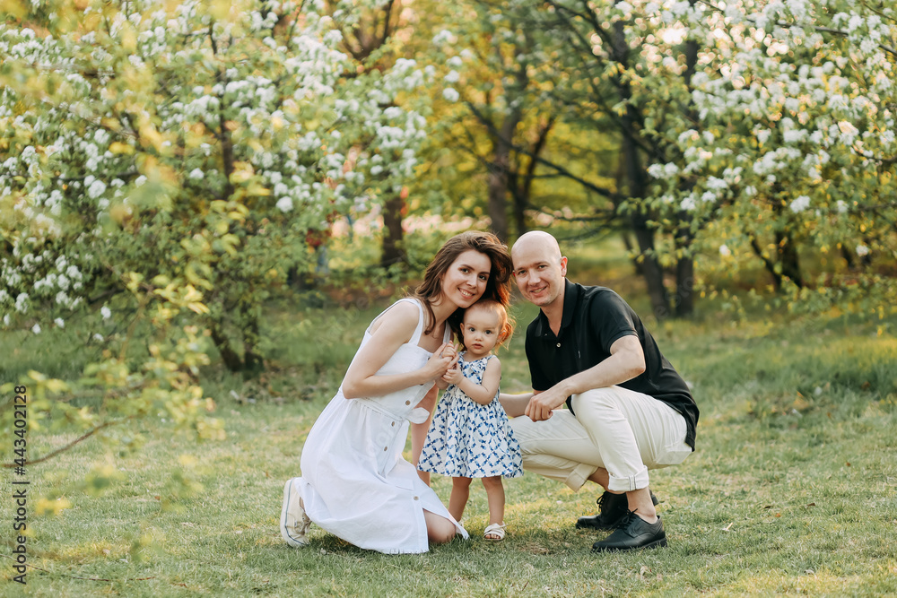 Fototapeta premium A happy young family with one small child walking having fun laughing spending time together in the park in nature on vacation in the summer outdoors, family day