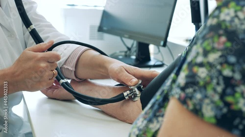 A patient is getting her blood pressure measured by a doctor