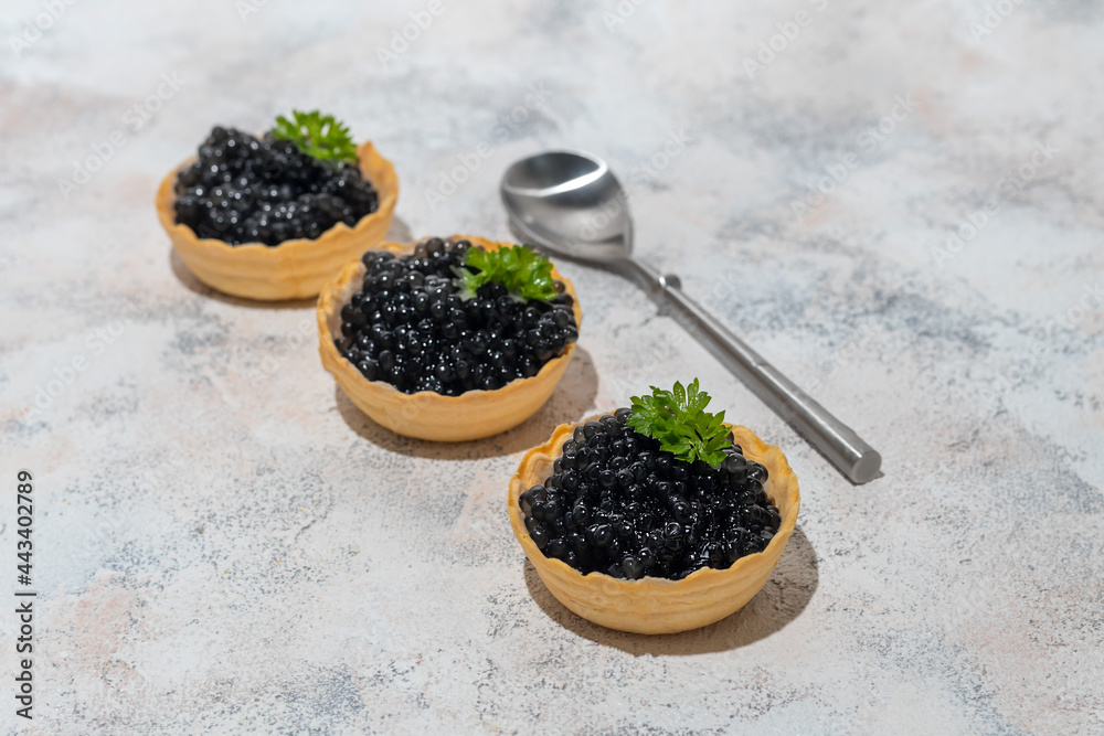 Black caviar in tartlets on a light background. Healthy food concept. Black caviar in tartlets on a light background. Healthy food concept.