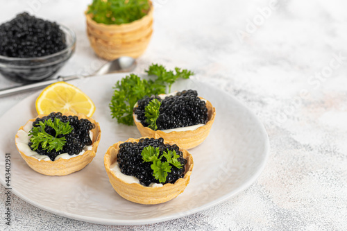 Black caviar in tartlets on a light background. Healthy food concept.