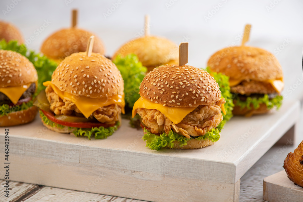 Set of Beef and Chicken mini burgers with cheese and lettuce with sticks on a wooden background - obrazy, fototapety, plakaty 