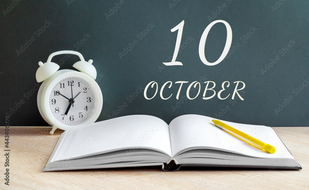 october 10. 10-th day of the month, calendar date.A white alarm clock, an open notebook with blank pages, and a yellow pencil lie on the table.Autumn month, day of the year concept october 10. 10-th day of the month, calendar date.A white alarm clock, an open notebook with blank pages, and a yellow pencil lie on the table.Autumn month, day of the year concept